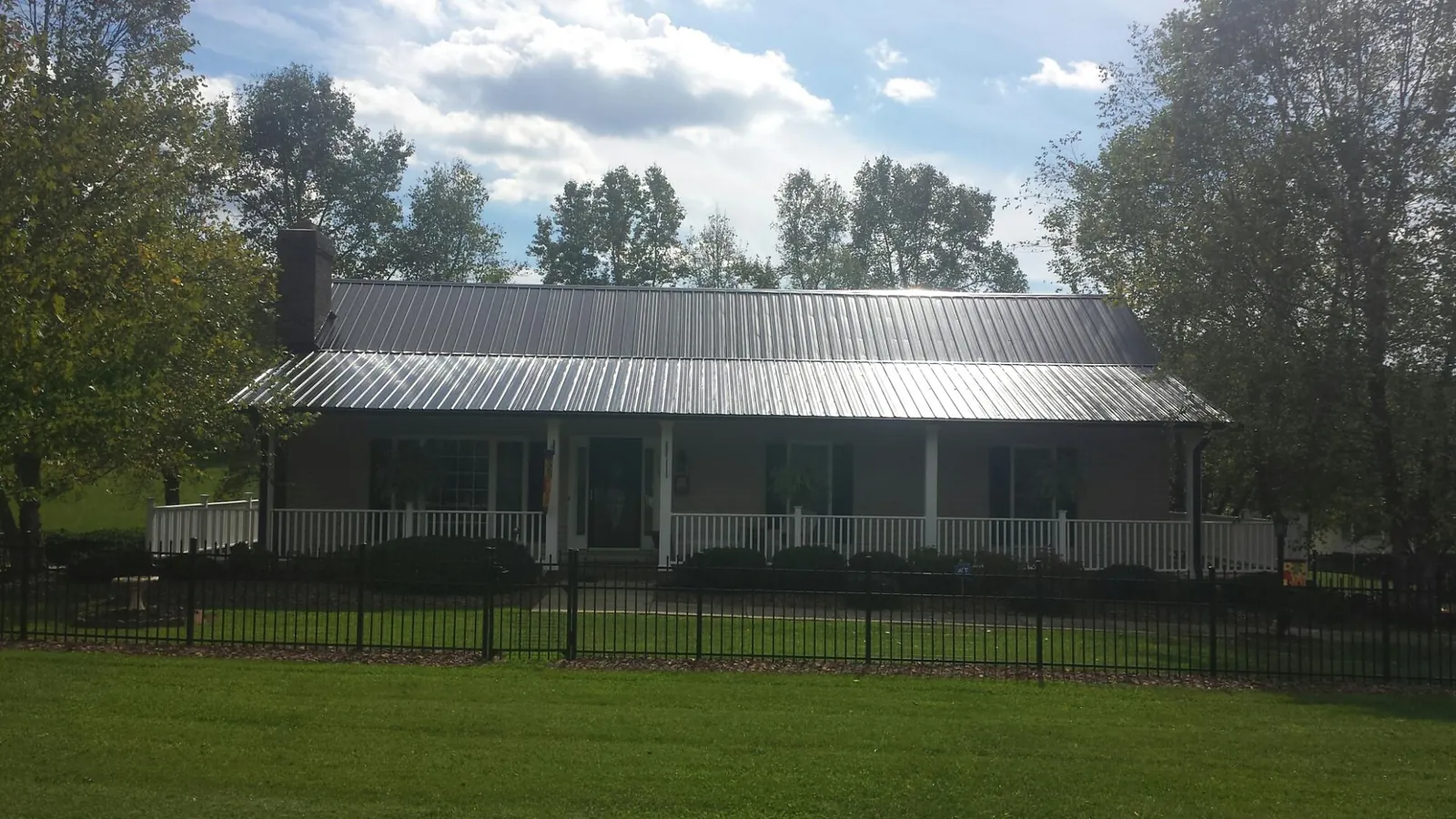 Gray metal roof on a brick ranch with a full width front porch — Gutter Guard Installation work by our crew in Spencer